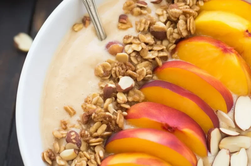 Peach Smoothie Bowl topped with crunchy granola and fresh peach slices.