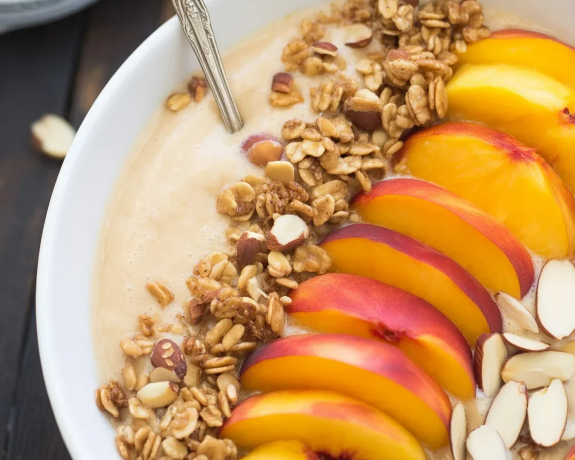 Peach Smoothie Bowl topped with crunchy granola and fresh peach slices.