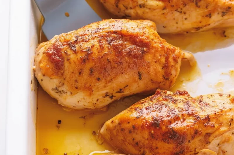 Oven roasted chicken breast served on a plate with herbs and spices.